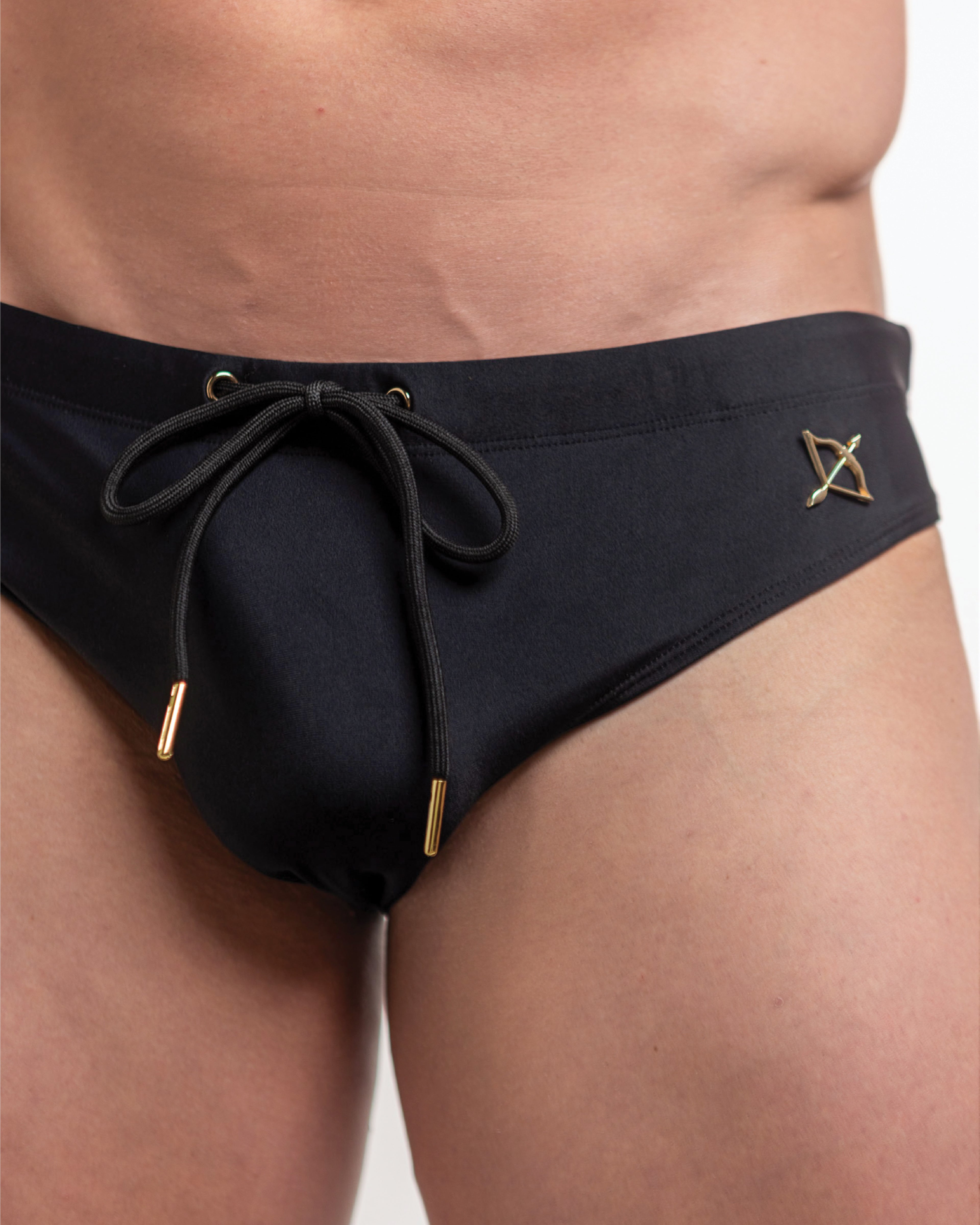 Black swim briefs with drawstring and gold accents on a neutral background